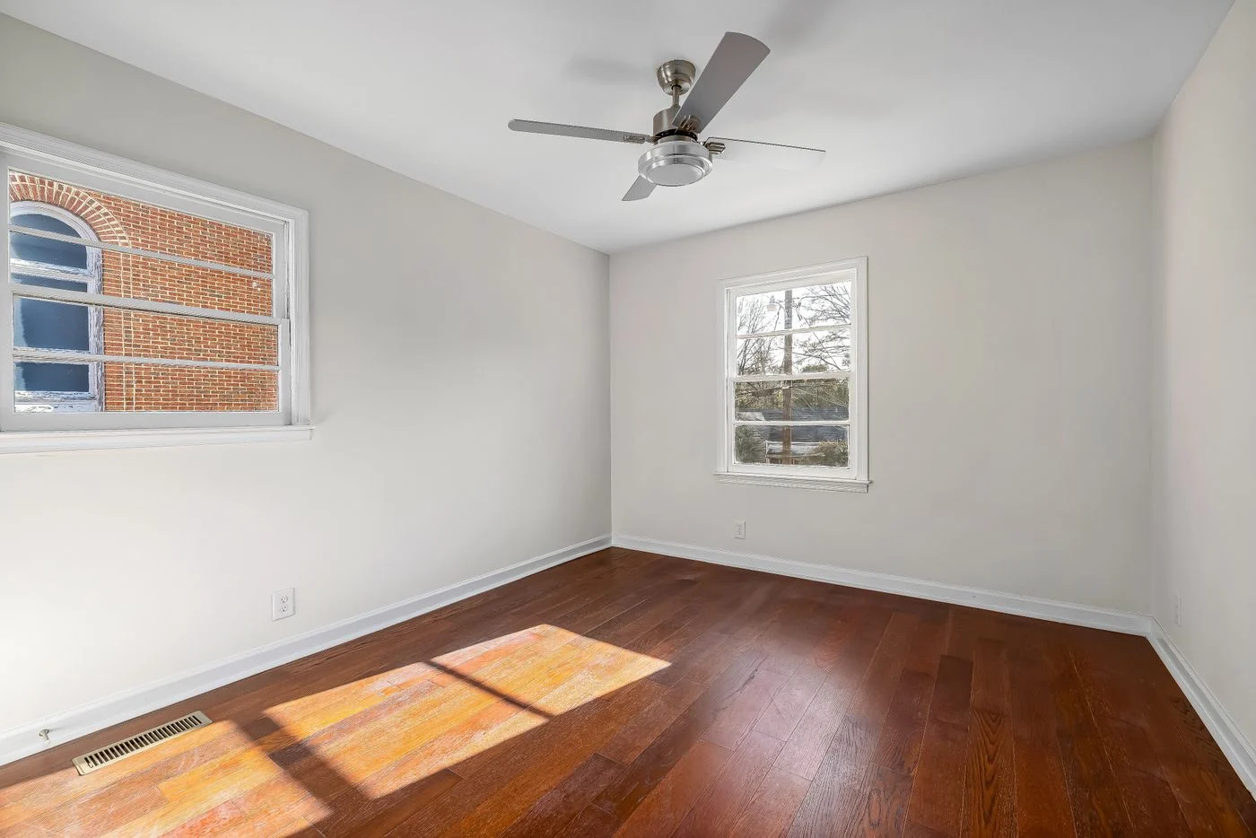 Empty bright room with wood flooring and a ceiling fan. — illustrative photograph.